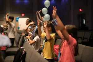 Group of little kids playing games, dancing in circle and having fun in camp