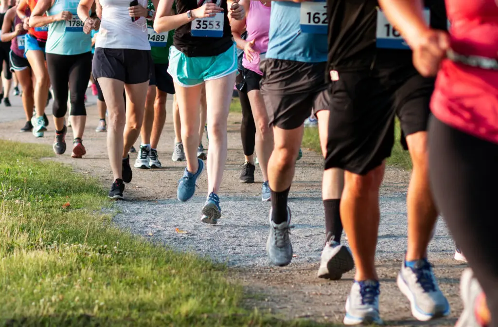 Legs of runners on a dirt path running a 5K race